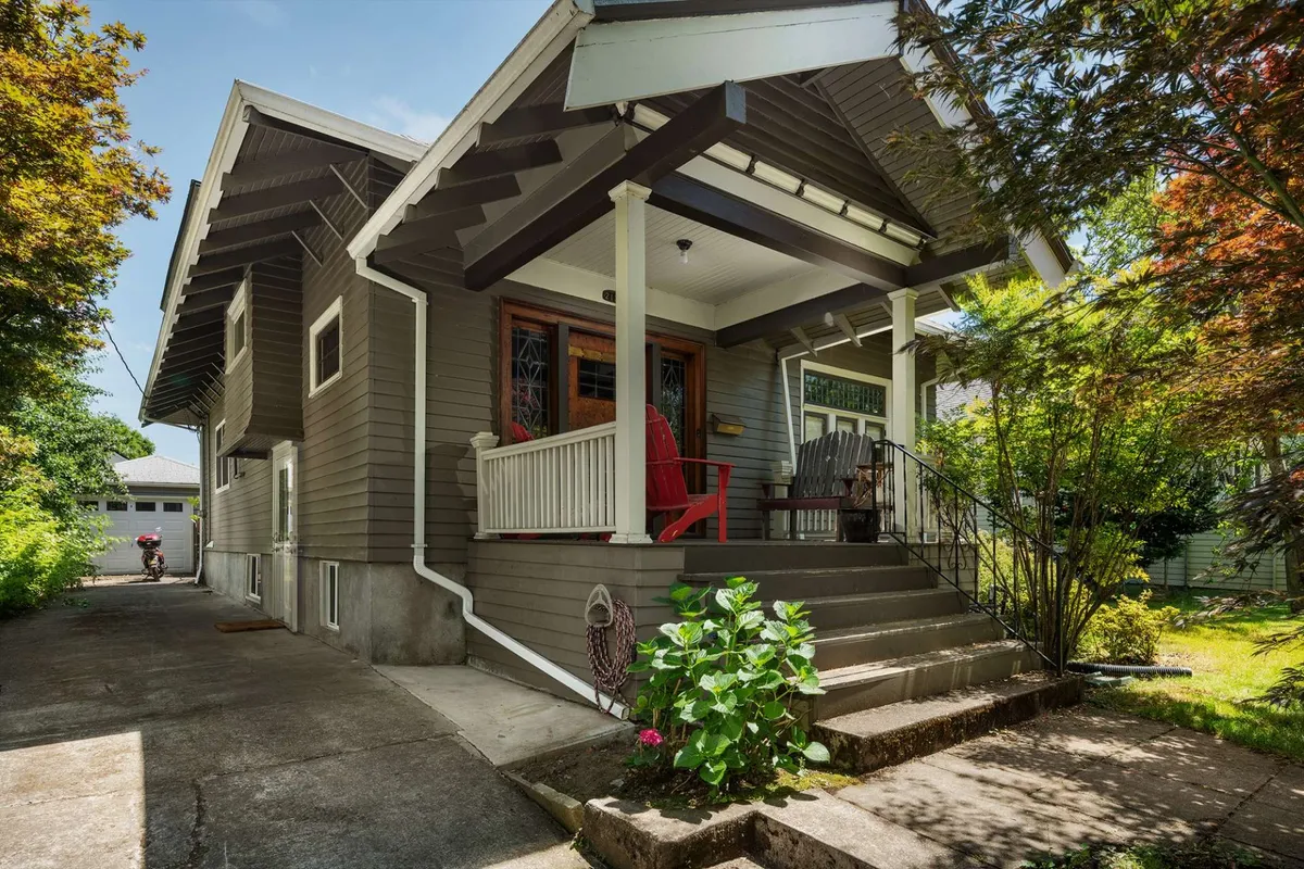 This image showcases the welcoming front porch of the retreat, with vibrant red chairs, a unique stained glass window, and lush greenery surrounding the entrance. The porch feels inviting, suggesting a comfortable spot to relax while taking in the neighborhood atmosphere.