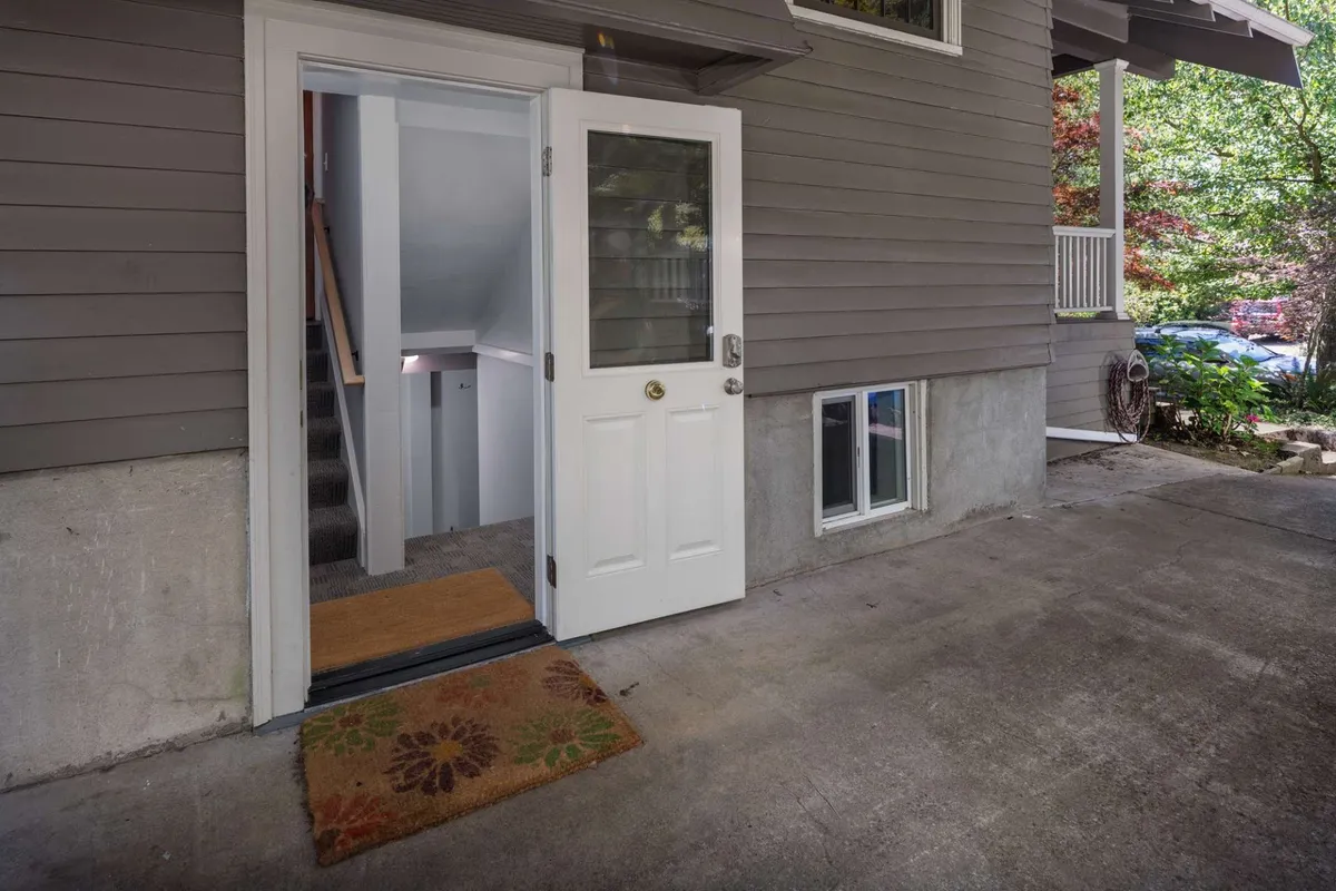 This exterior image features an open door with a doormat and a staircase leading down, providing a literal visual of the transition from outside to inside. It hints at a private, welcoming entryway that sets the tone for arrival.
